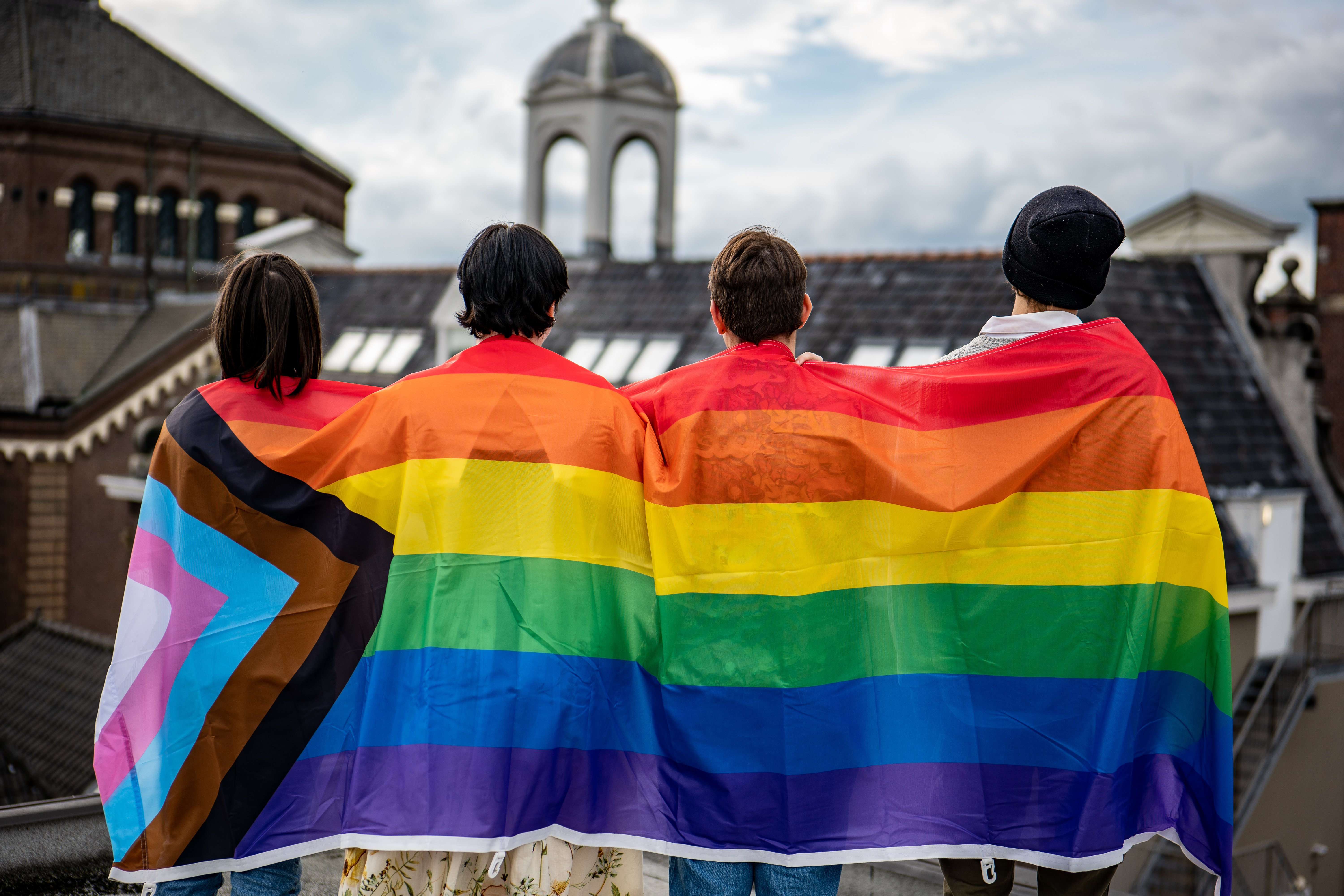 4 mensen en een regenboogvlag