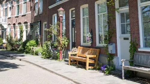 Voorbeeld van een geveltuintje in de stoep voor een woning met een bankje erbij