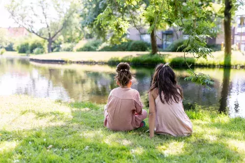 twee kinderen aan de oever in de schaduw
